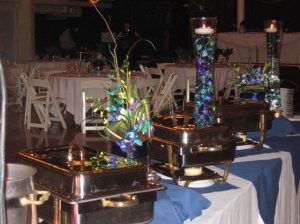 a bouquet of flowers used as a catering centerpiece set up next to a buffet station