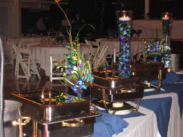 a bouquet of flowers used as a catering centerpiece set up next to a buffet station
