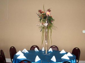 a bouquet of flowers on top of a blue table cloth with white napkins used for catering