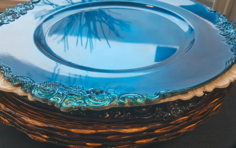 a stack of metallic plates with a blue plate on top for catering